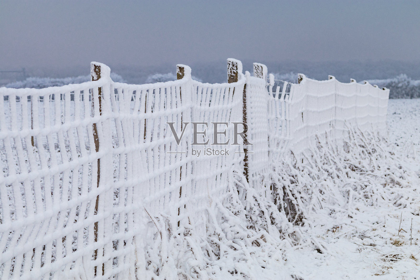 冬季雪景中完全被雪覆盖的栅栏照片摄影图片