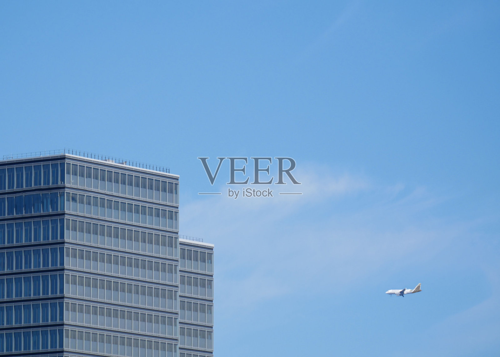 飞机飞过建筑附近的城市，背景是蓝天照片摄影图片