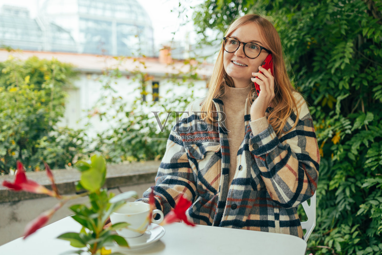 近距离的一个美丽的年轻金发女子在咖啡馆，在咖啡馆休息时打电话的智能手机。照片摄影图片