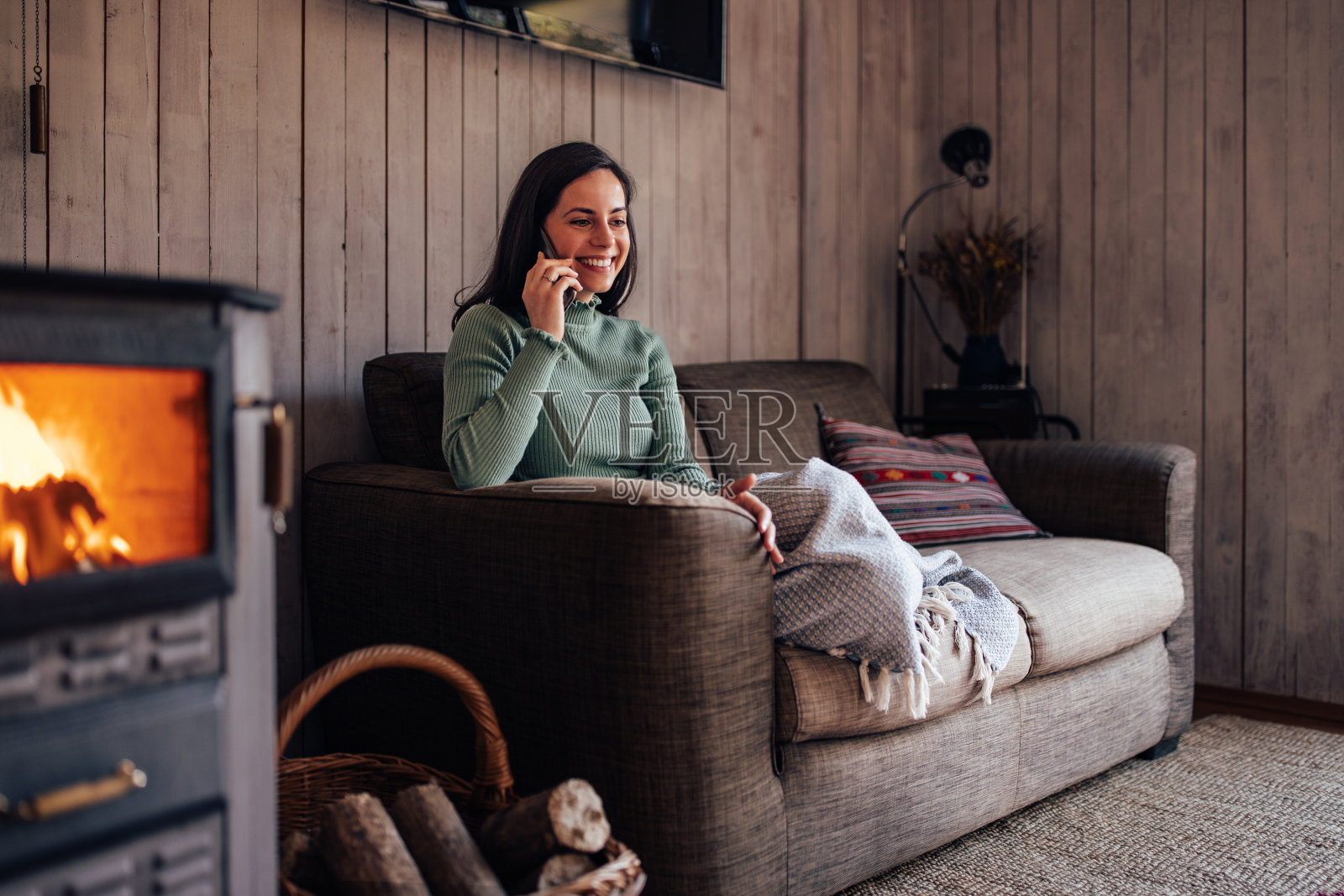 看起来很舒服的女孩，在沙发上盖着毯子，一边打电话一边享受。照片摄影图片