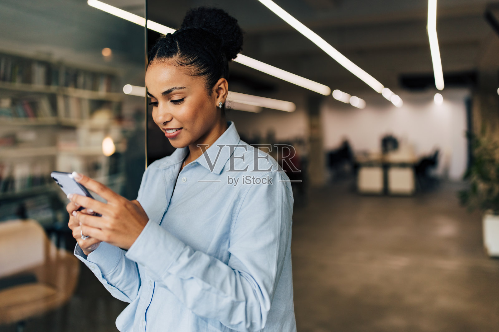 快乐的非洲女商人与扭曲的头发使用电话在工作场所。照片摄影图片