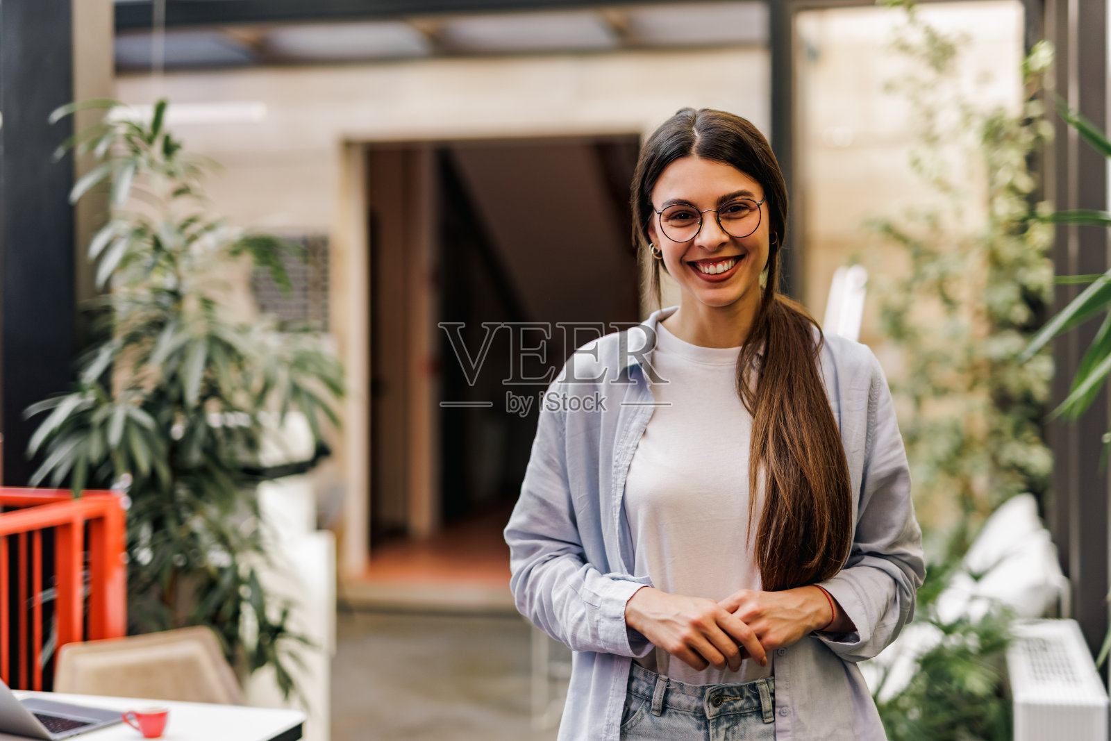 一个微笑的女性肖像，握着她的手，看着相机。照片摄影图片