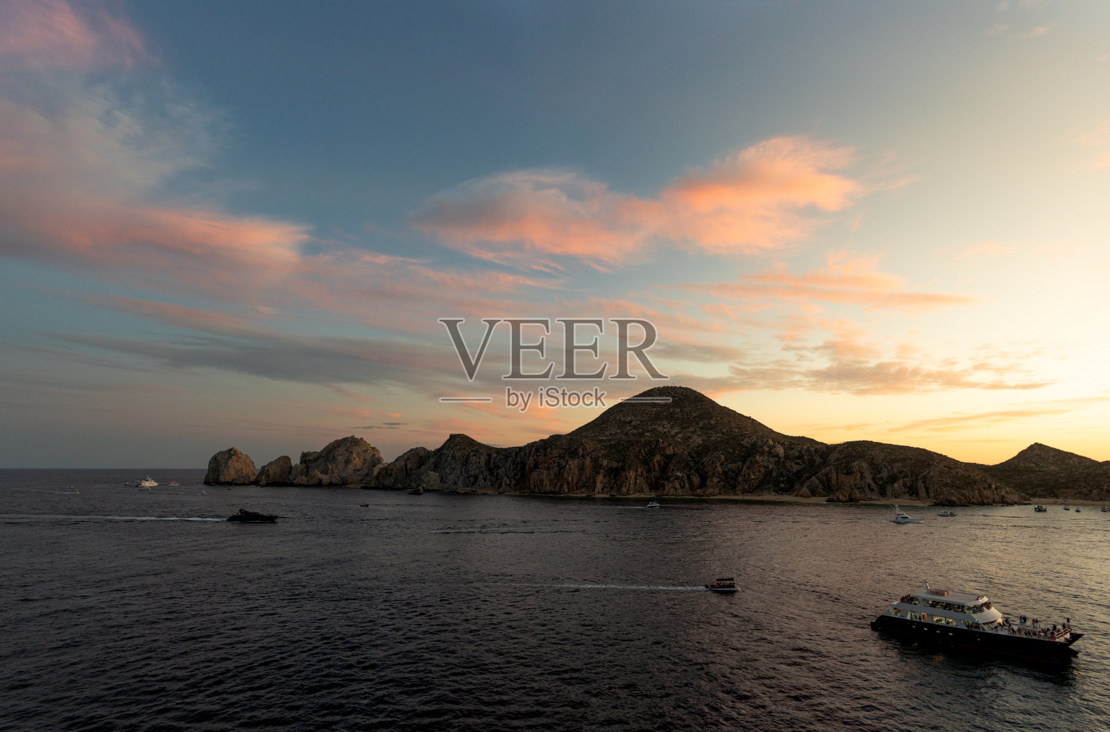 卡波圣卢卡斯的巴哈半岛夜景，前景中有科尔特斯海和船只，戏剧性的云景日落照片摄影图片