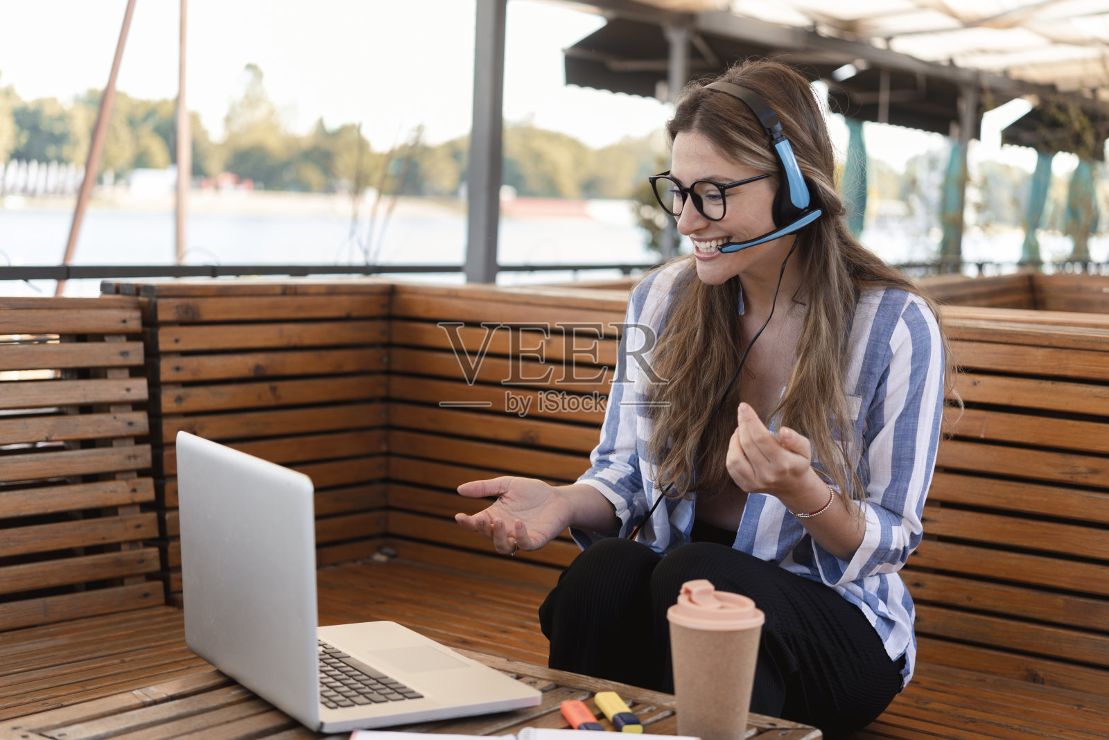 快乐的年轻女子在河边的咖啡馆享受和在线工作照片摄影图片