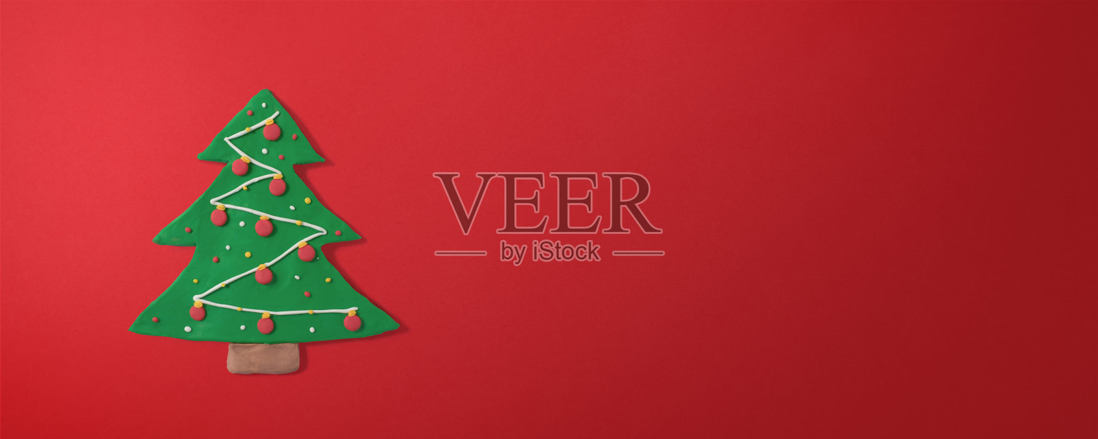 姜饼圣诞树形状的饼干，用橡皮泥手工制作，红色渐变背景与复制空间。圣诞和新年贺卡概念照片摄影图片