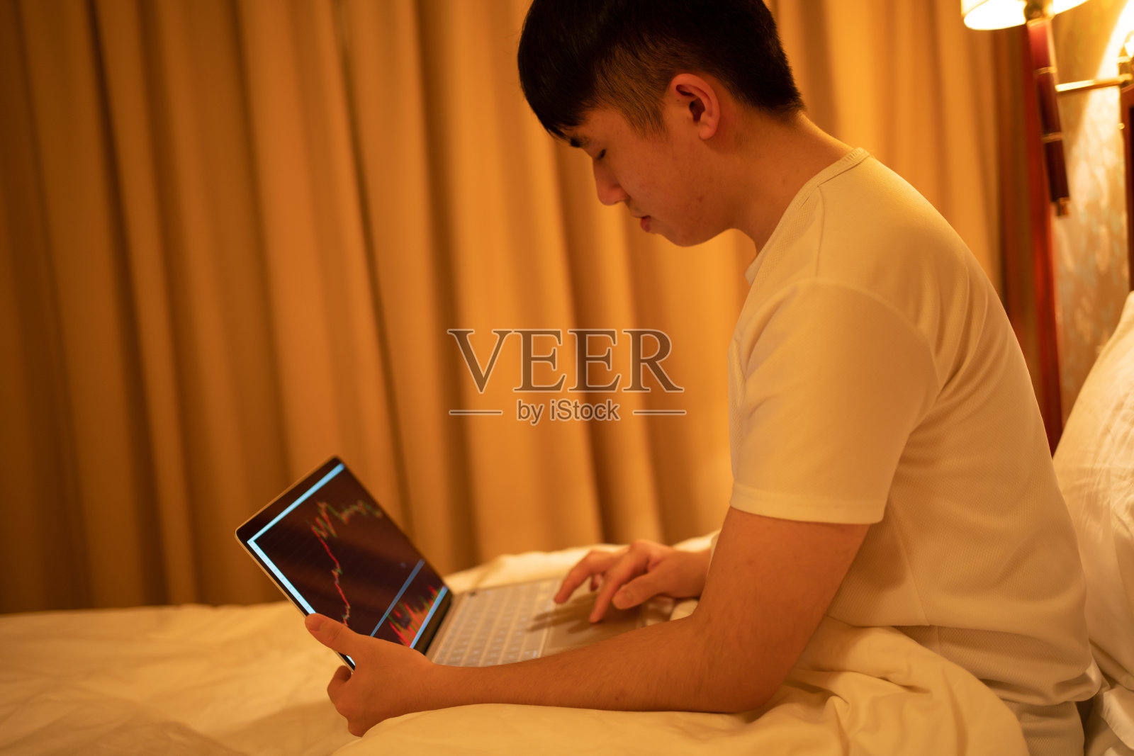 男子在床上查看股票市场照片摄影图片