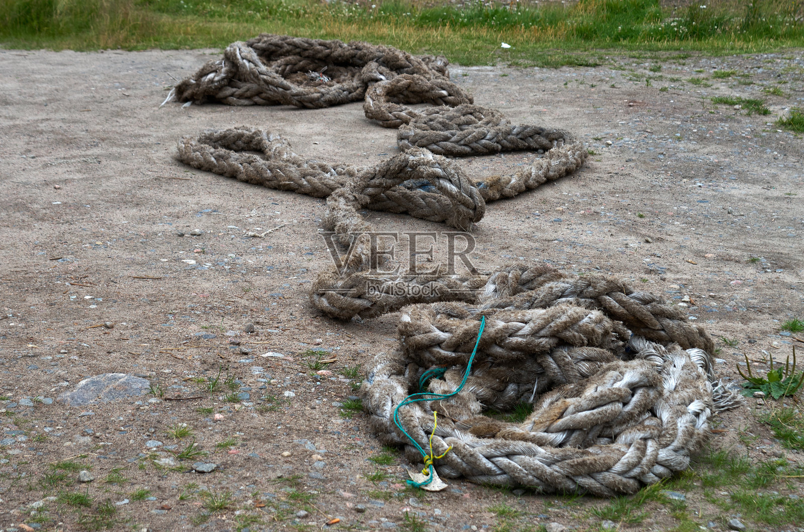 海边的地上躺着一根又粗又旧的缆绳照片摄影图片