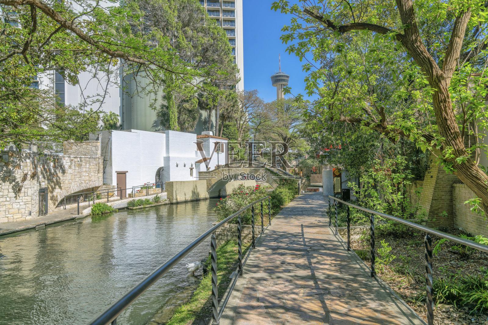 在阳光明媚的日子里，德克萨斯州圣安东尼奥的河边步道两旁是小径和建筑物照片摄影图片