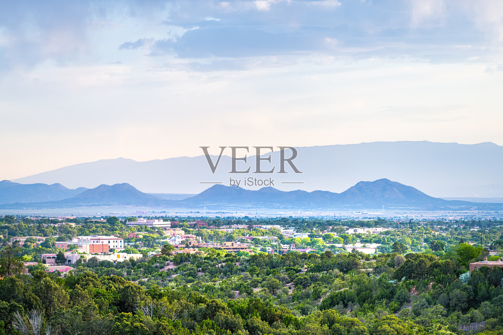 日落在圣菲，新墨西哥州的天际线与黄金时间的光，夏季植物的城市景观建筑与圣格里德基督山剪影照片摄影图片