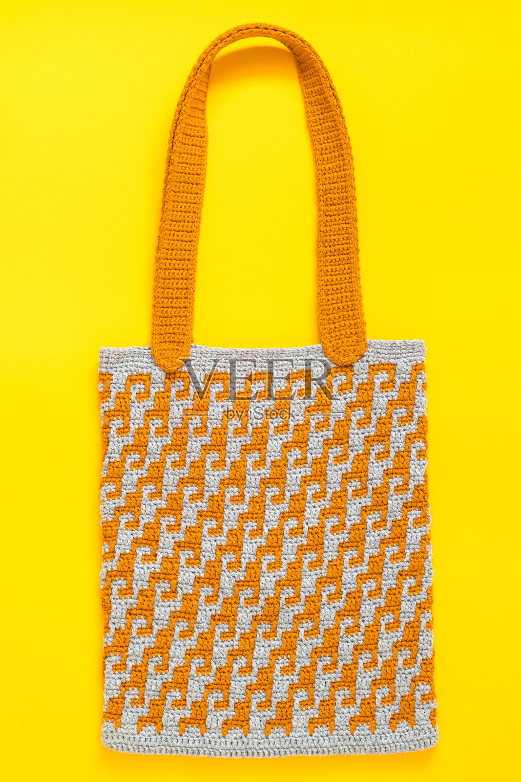 橙色灰色钩针袋与抽象的模式在黄色的背景。照片摄影图片