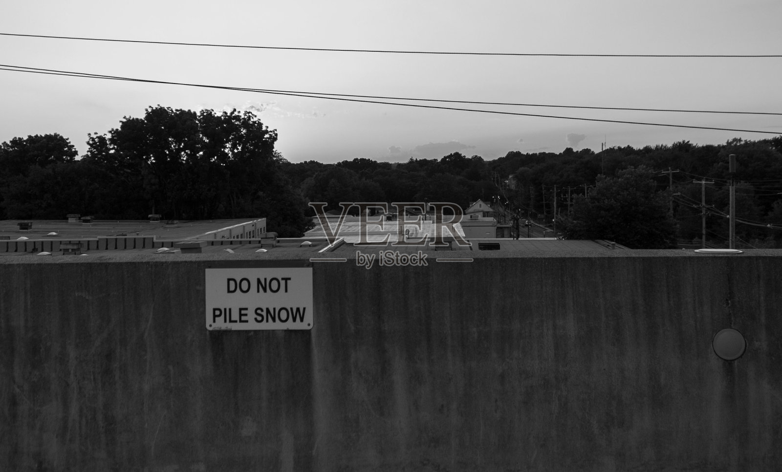 黑色和白色的拍摄一个不要在这里堆雪的街道标志在墙上与自然的背景照片摄影图片