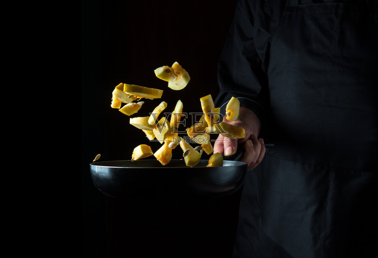 厨师在平底锅里准备西葫芦。在黑暗的背景上烹饪蔬菜和健康的素食。免费广告位照片摄影图片