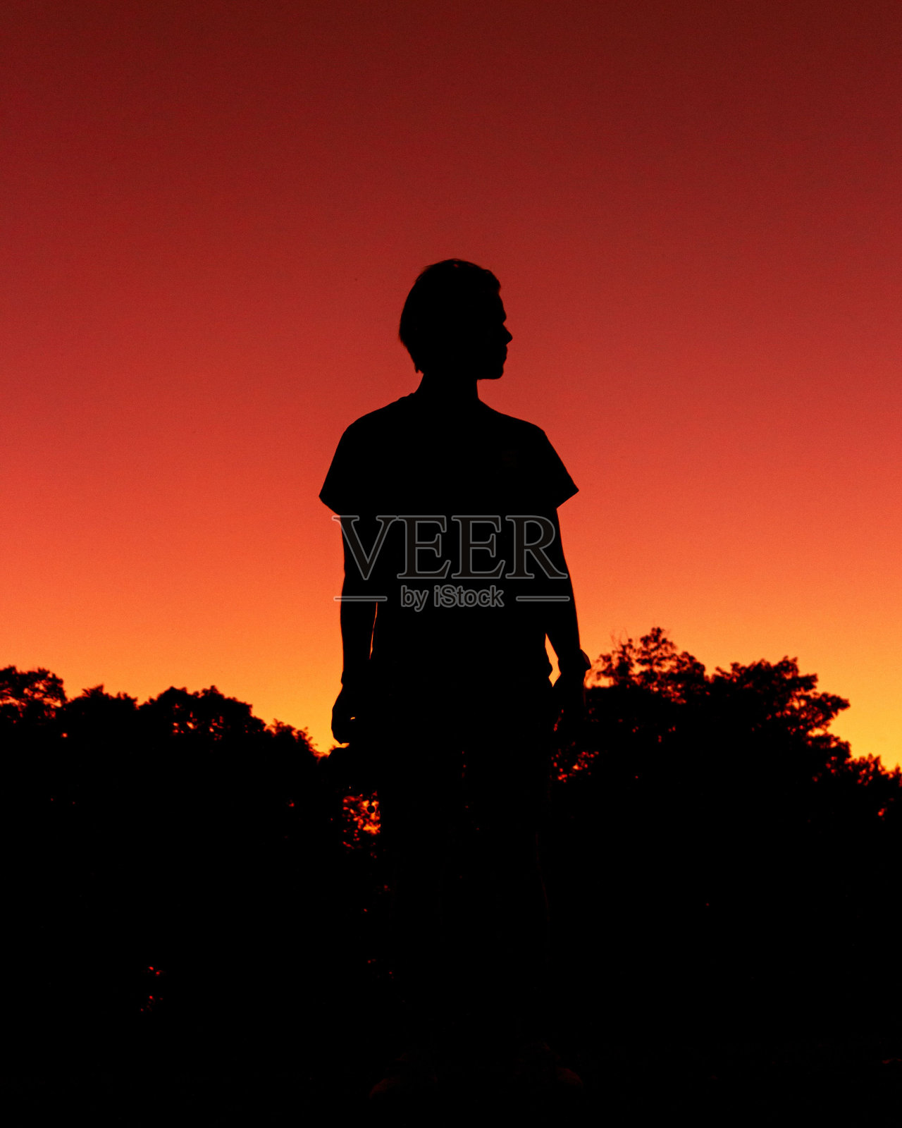 一个人的垂直剪影与一个充满活力的红色日落的背景照片摄影图片