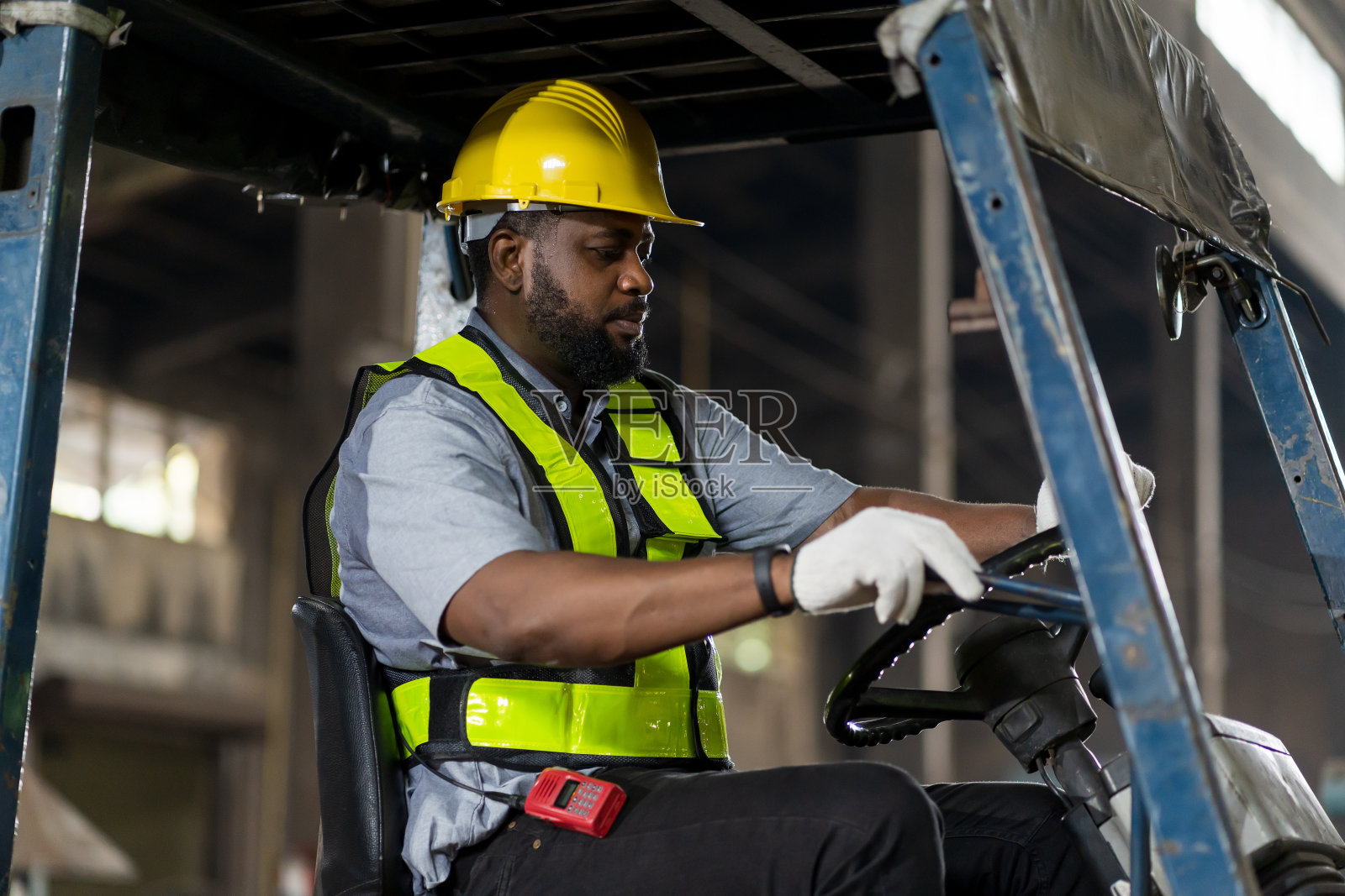 非裔美国男性工人在工业工厂驾驶和操作叉车。男工人戴安全帽，穿制服驾驶叉车照片摄影图片