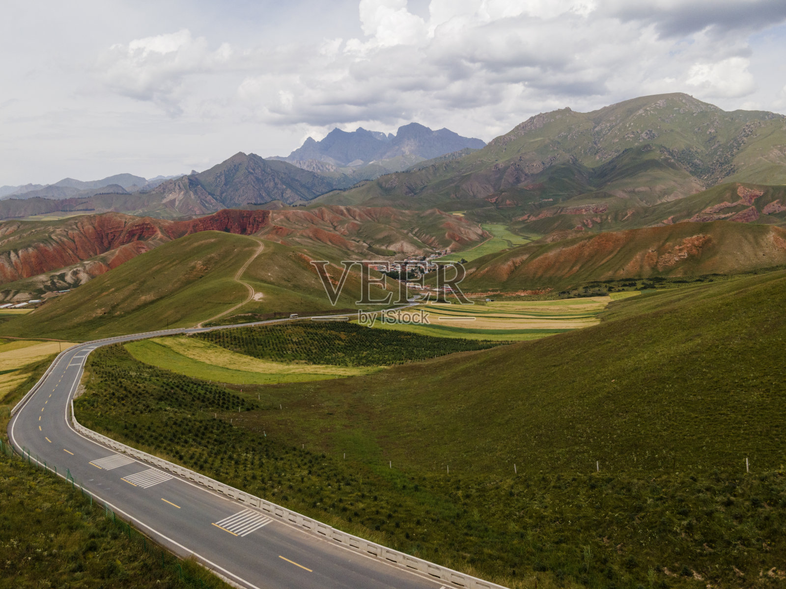 路到一个群山环抱的村庄，丹霞地貌在中国青海照片摄影图片