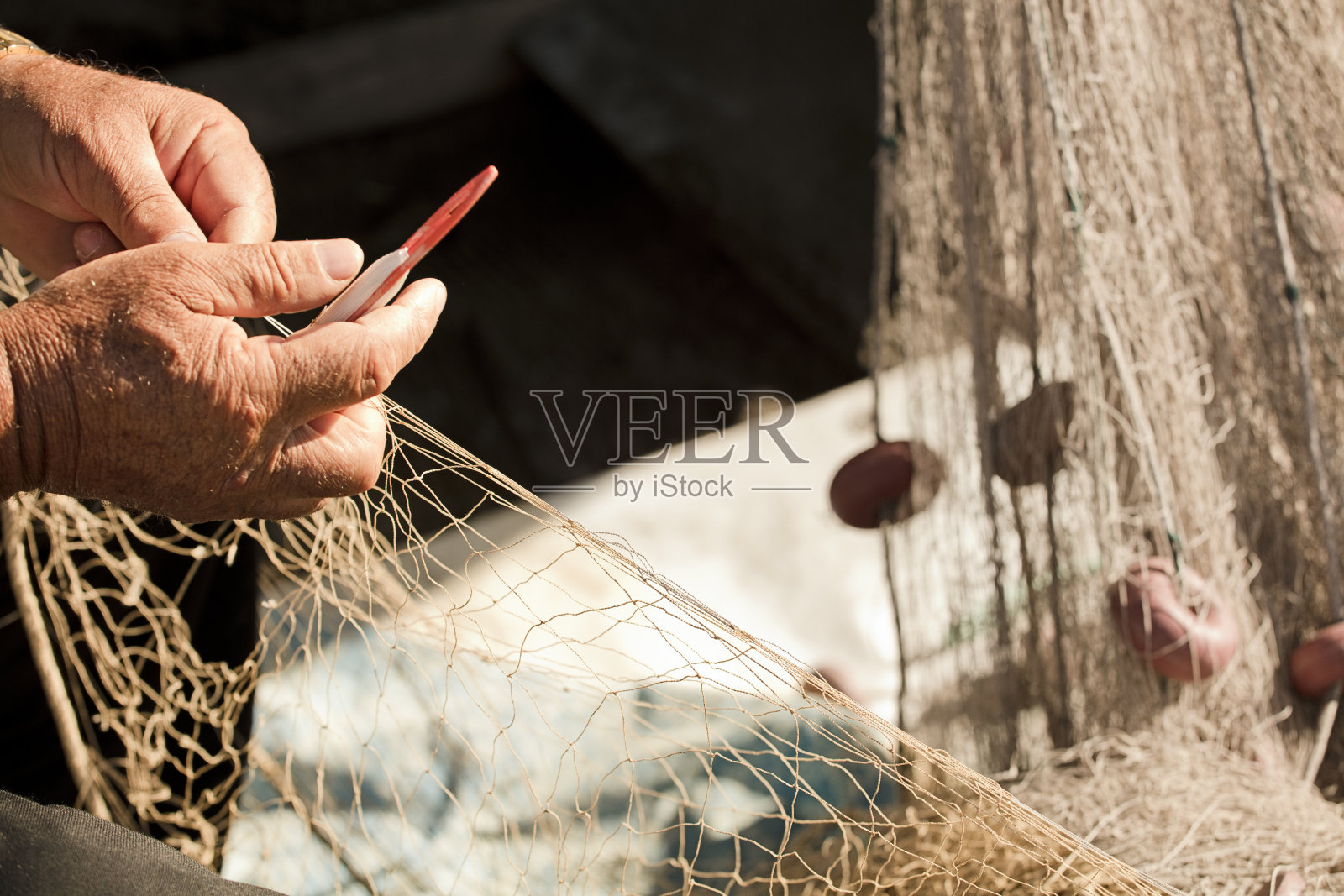 渔夫手中的渔网，他用针线编织和修补照片摄影图片