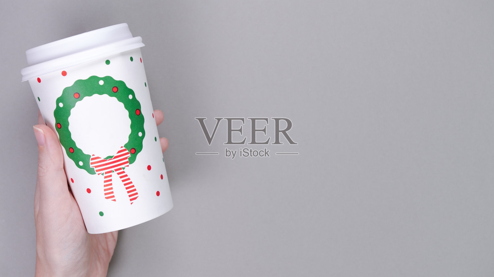 手持一次性咖啡纸杯，灰色背景。圣诞或新年假期祝福纸咖啡杯模板。平铺，俯视图，复制空间。照片摄影图片