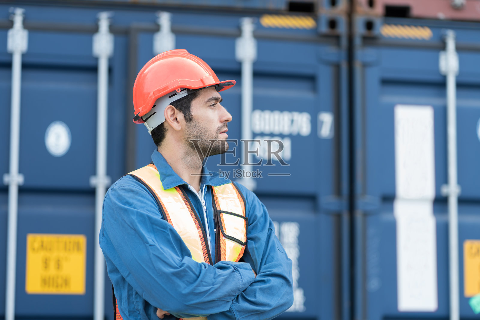在商业码头工作的男性货柜堆场工人肖像。男主管集装箱堆场工人戴安全帽，穿制服在集装箱码头堆场工作照片摄影图片