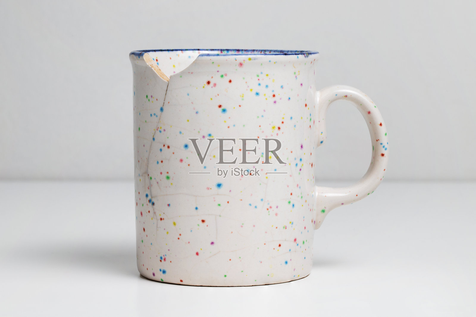 白色桌子上的破杯子。破碎的杯子照片摄影图片