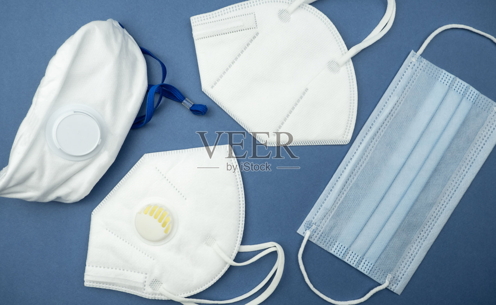 蓝色背景上不同类型的医用口罩。一次性医用口罩和呼吸器。病毒防护概念。照片摄影图片