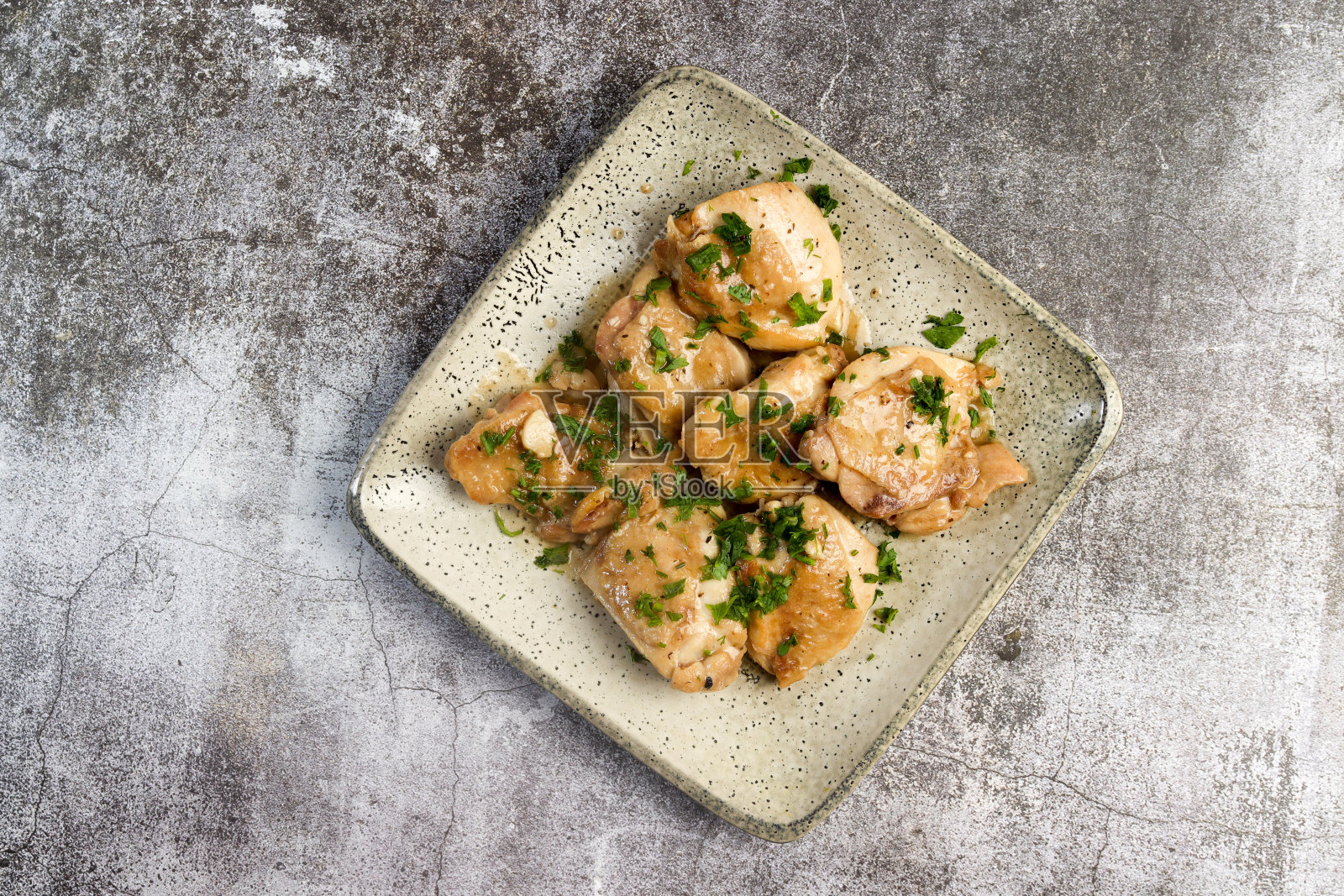 烤蒜香鸡腿配香草，放在深色背景的方形盘子上。俯视图，平面布局照片摄影图片