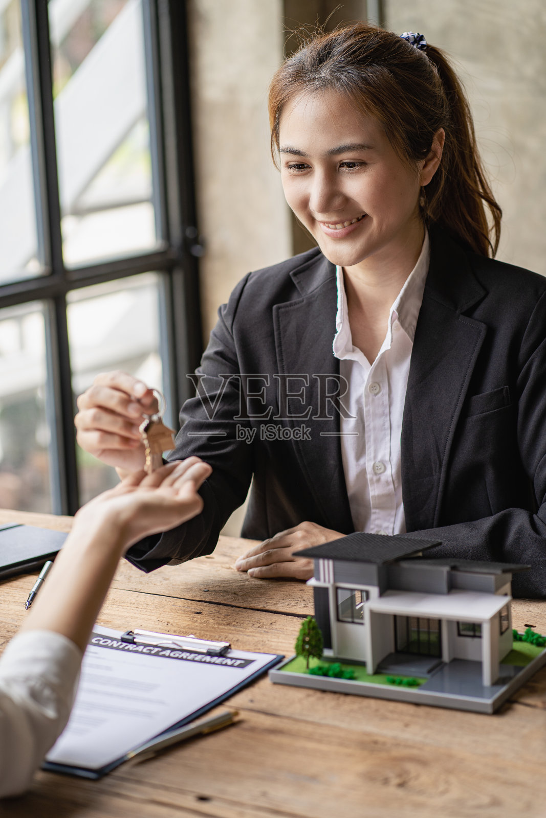 房屋和房地产交易业务房地产经纪人向签署房屋贷款保单的女性房主发放钥匙。房地产经纪人与客户签订合同前。照片摄影图片