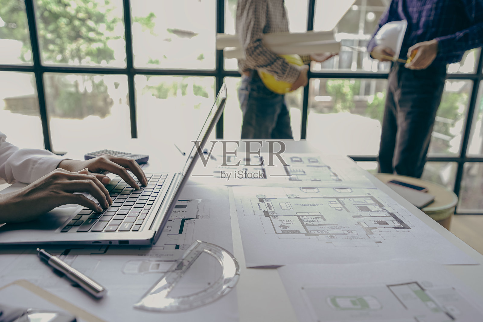 工程团队会议，同事们在办公室办公桌前讨论和审查蓝图，工程师和工人在工作场所规划建筑和翻新建筑项目照片摄影图片