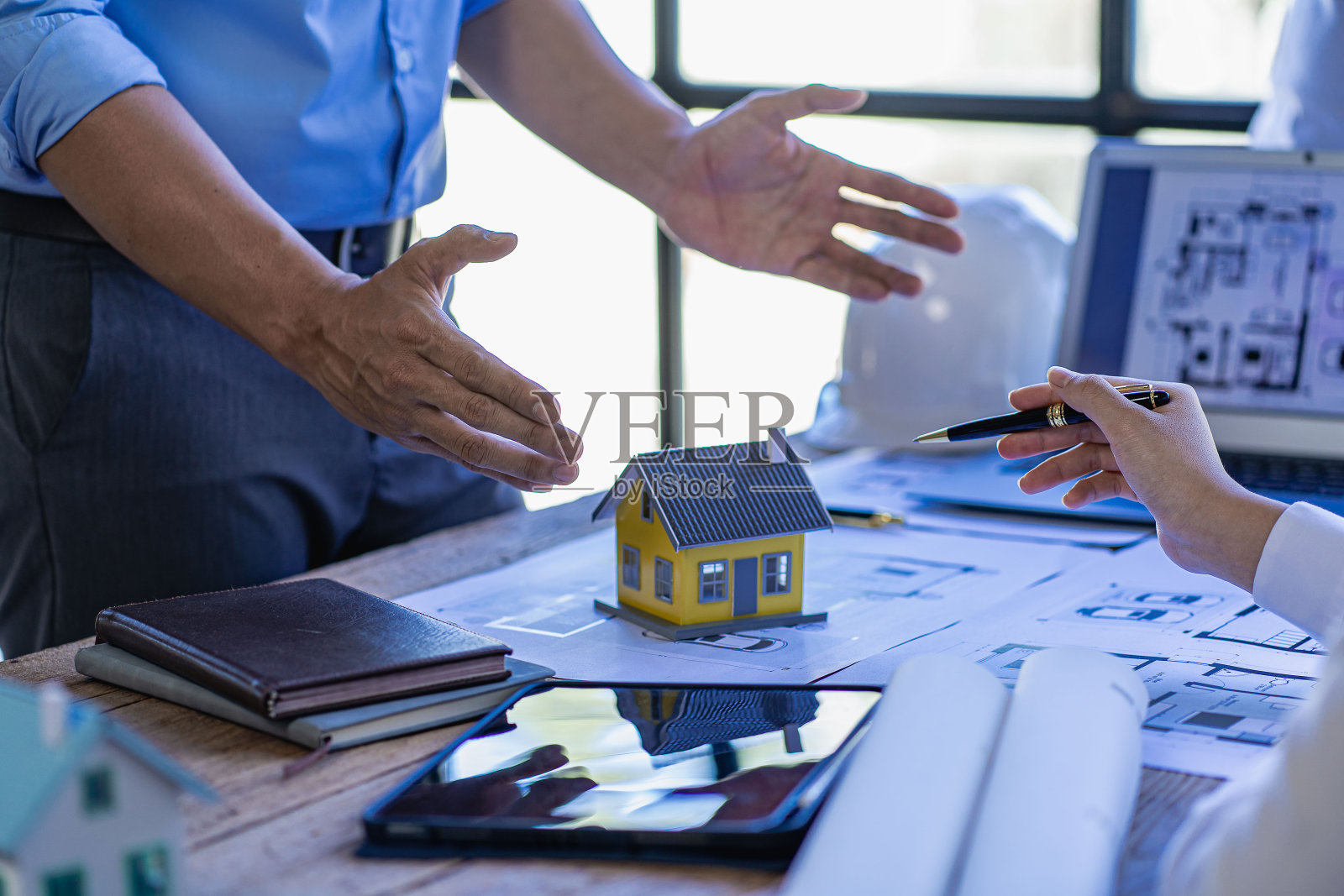 工程团队会议，同事们在办公室办公桌前讨论和审查蓝图，工程师和工人在工作场所规划建筑和翻新建筑项目照片摄影图片