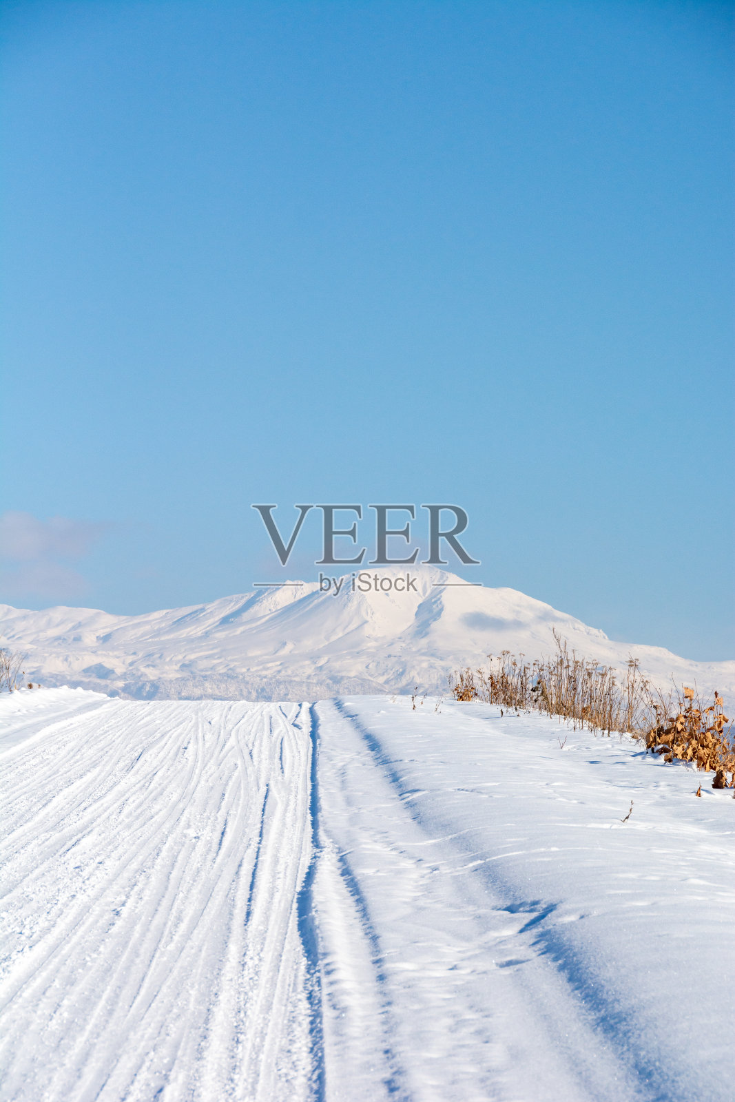 阳光明媚的冬日，雪路和雪山照片摄影图片