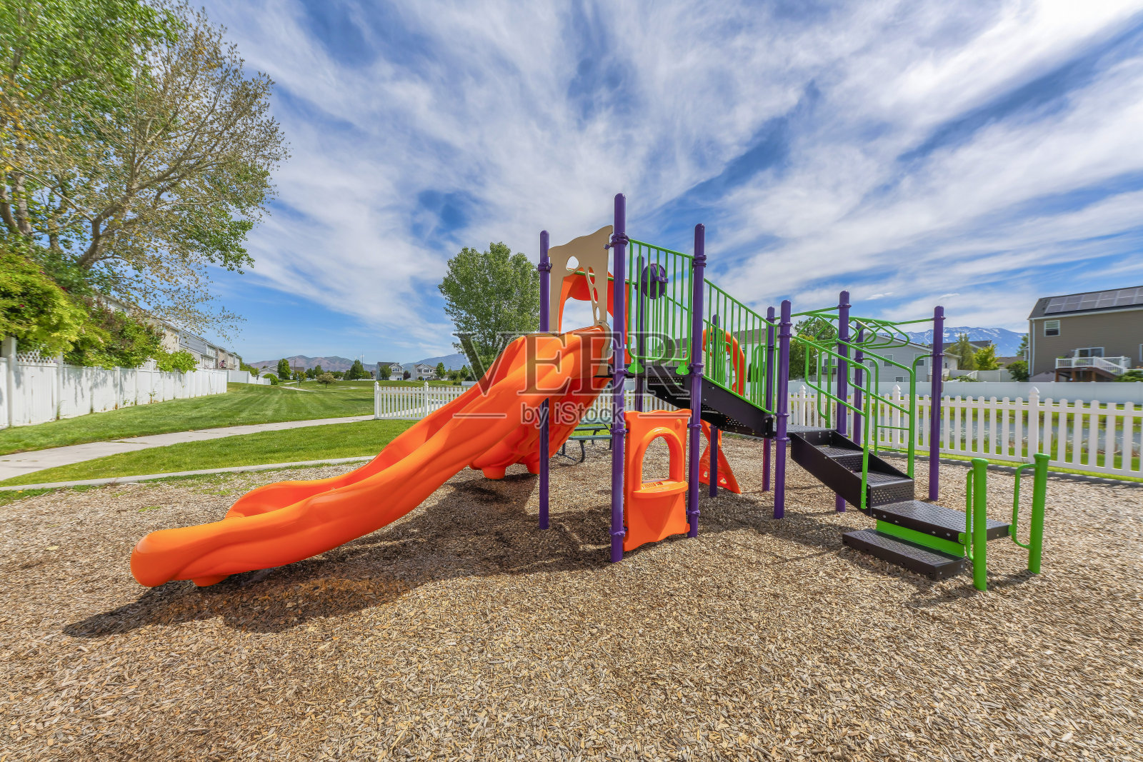 犹他州山谷一个有尖桩栅栏的社区操场上的彩色滑梯照片摄影图片