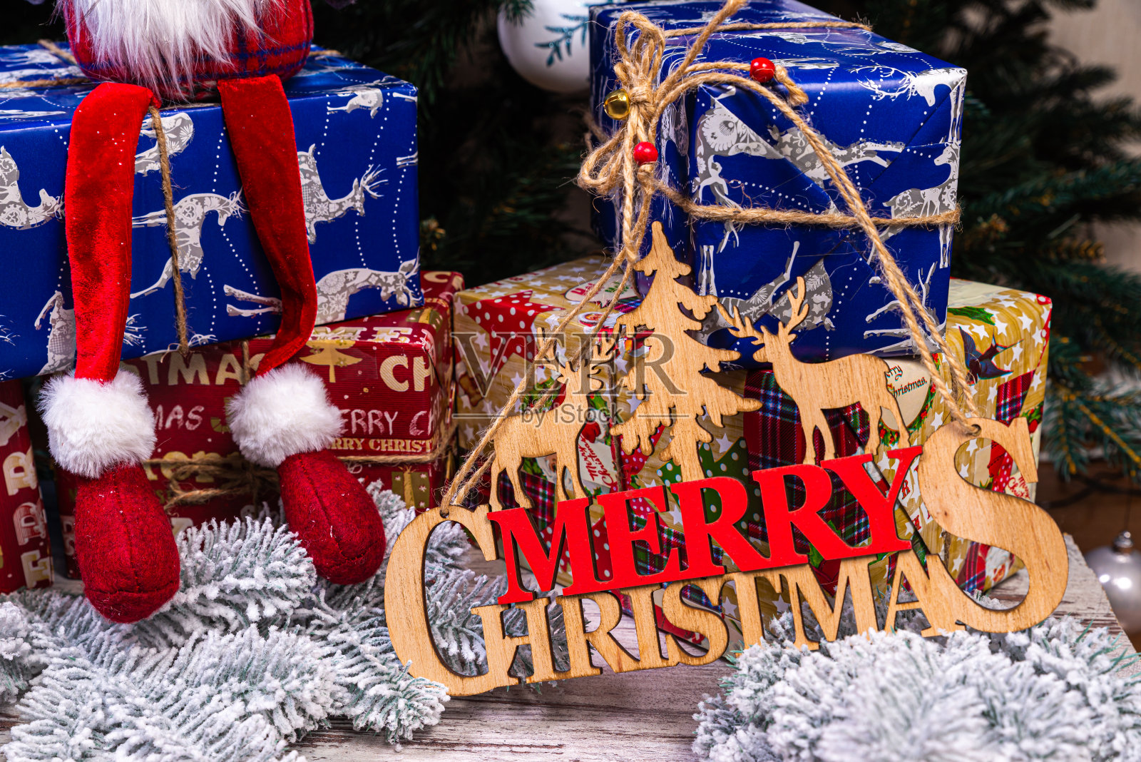 新年树上的铭文“冬天”。在白雪覆盖的背景下，云杉树枝上有蓝色、白色的球和云杉蛋筒，还有一个装有礼物的盒子。圣诞节照片摄影图片