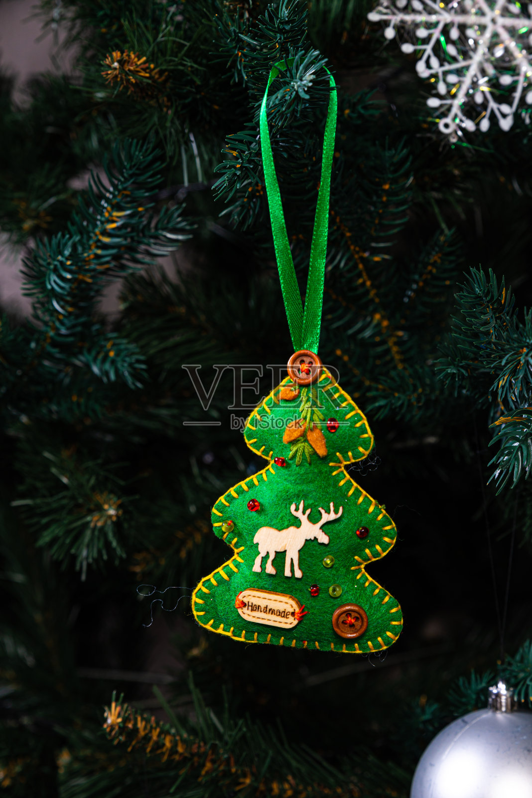 有创意的手工diy爱好。制作手工制作的圣诞饰品和球与感觉云杉树。圣诞树上有彩色的球和礼品盒，白色的砖墙上有蓝白色的球照片摄影图片