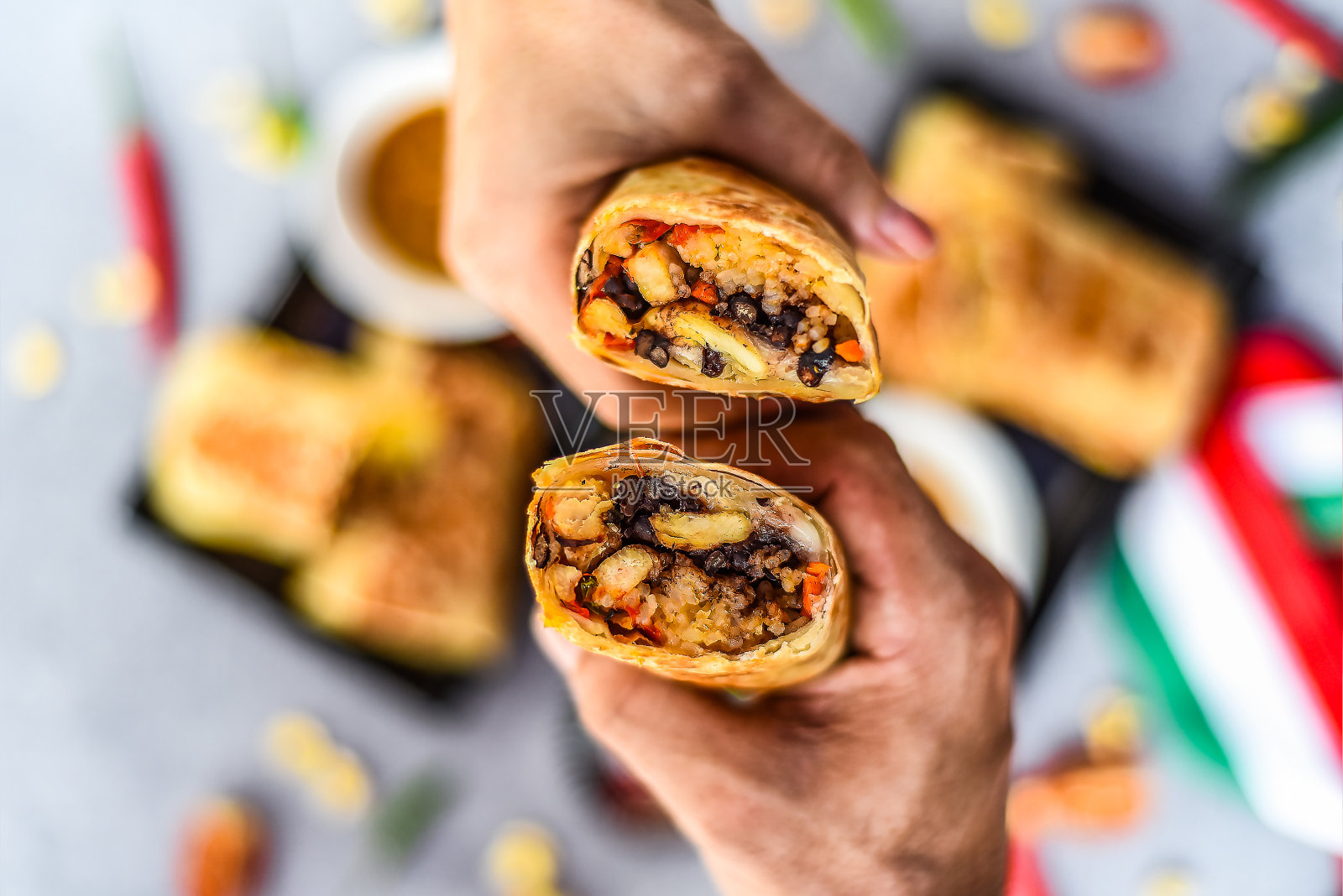 手拿墨西哥卷饼配鸡肉、米饭、豆子、奶酪配博拉查酱汁照片摄影图片