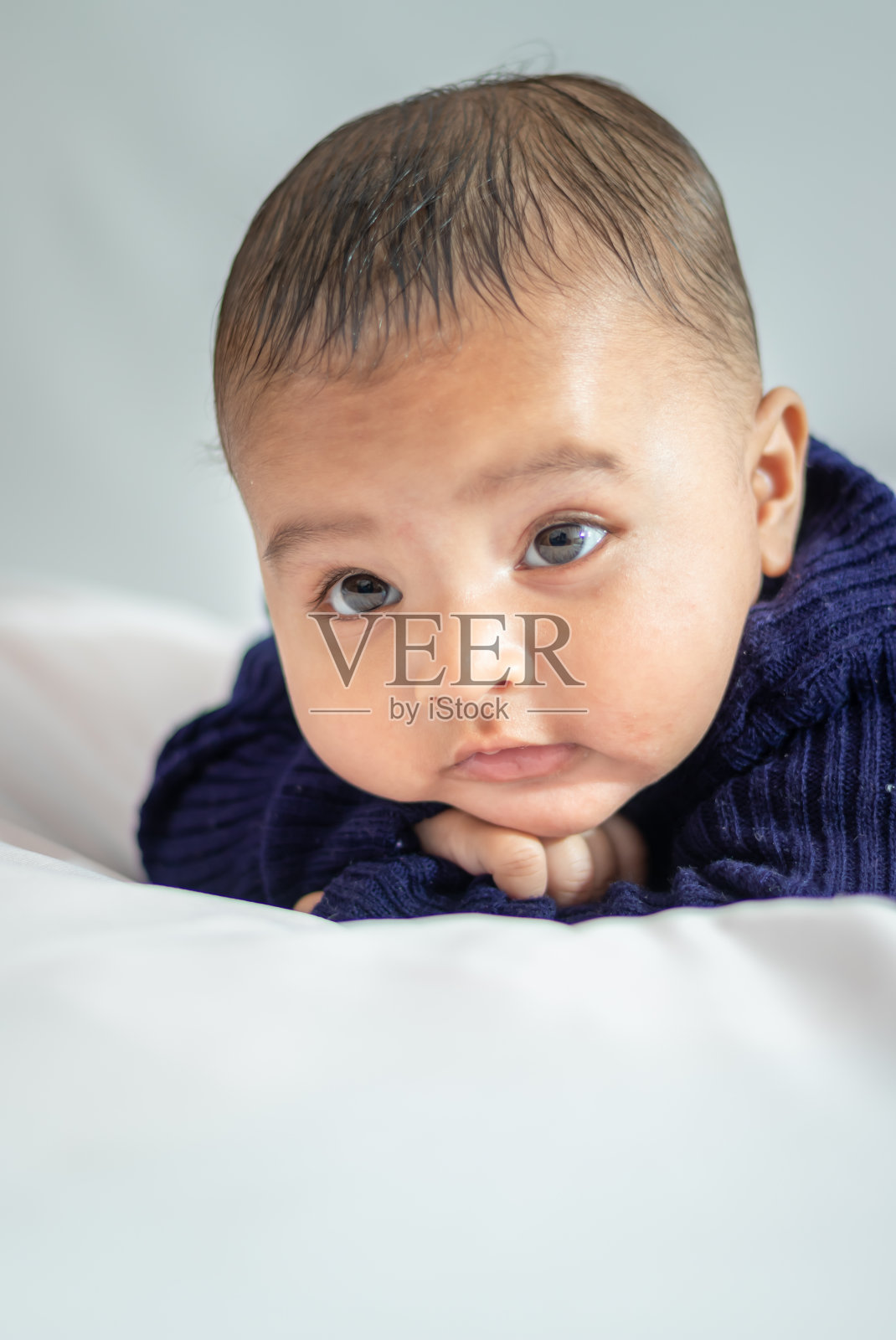 婴儿男孩躺在可爱的面部表情与白色背景在室内照片摄影图片