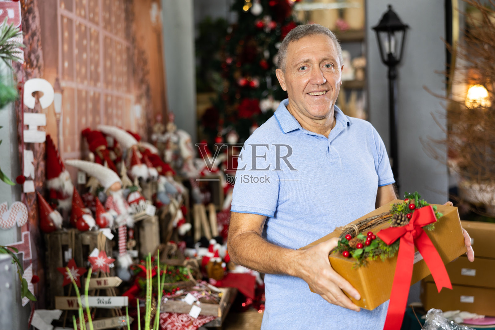 一个老人的肖像与盒子的礼物在圣诞礼物商店照片摄影图片