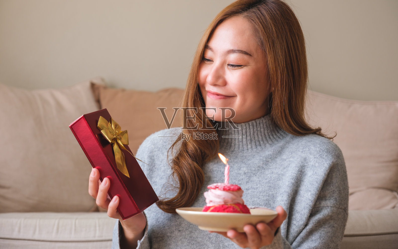 肖像形象的年轻女子拿着一个礼品盒和生日蛋糕与蜡烛照片摄影图片