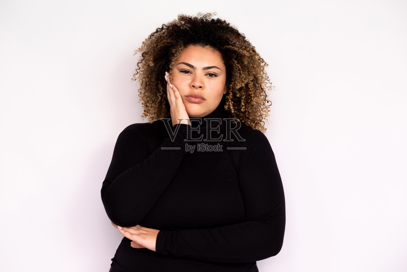 不高兴的年轻女子把手放在她的脸颊上照片摄影图片