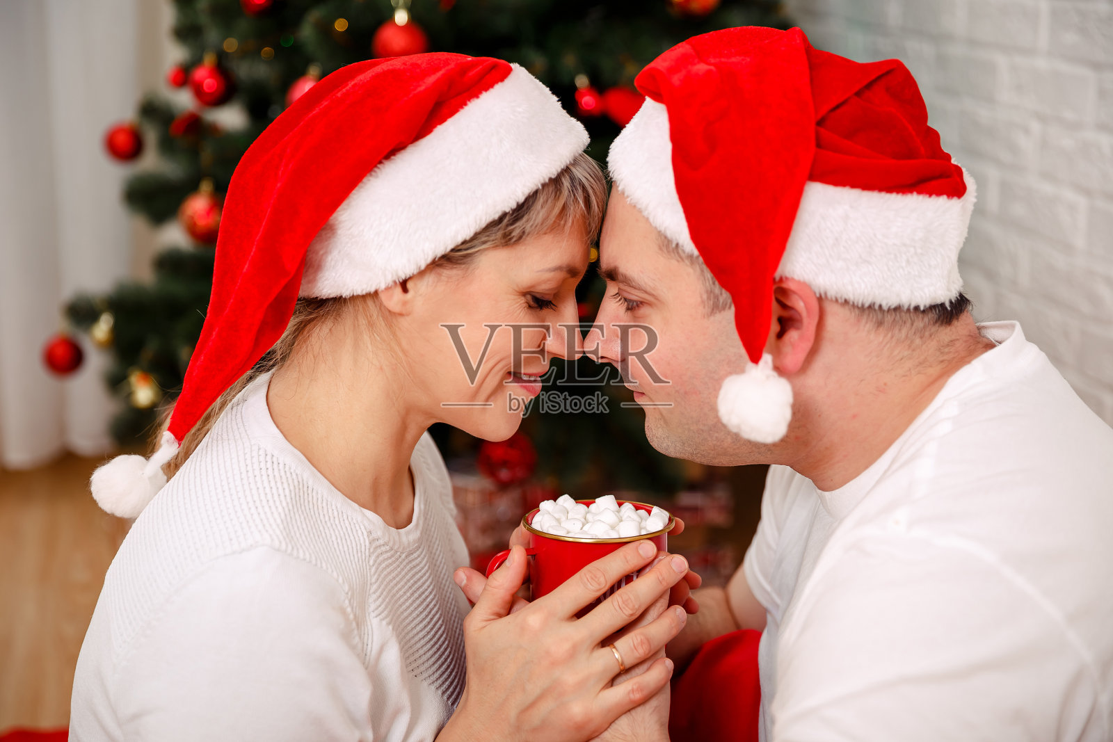 可爱的小情侣在平安夜在家喝热巧克力。照片摄影图片