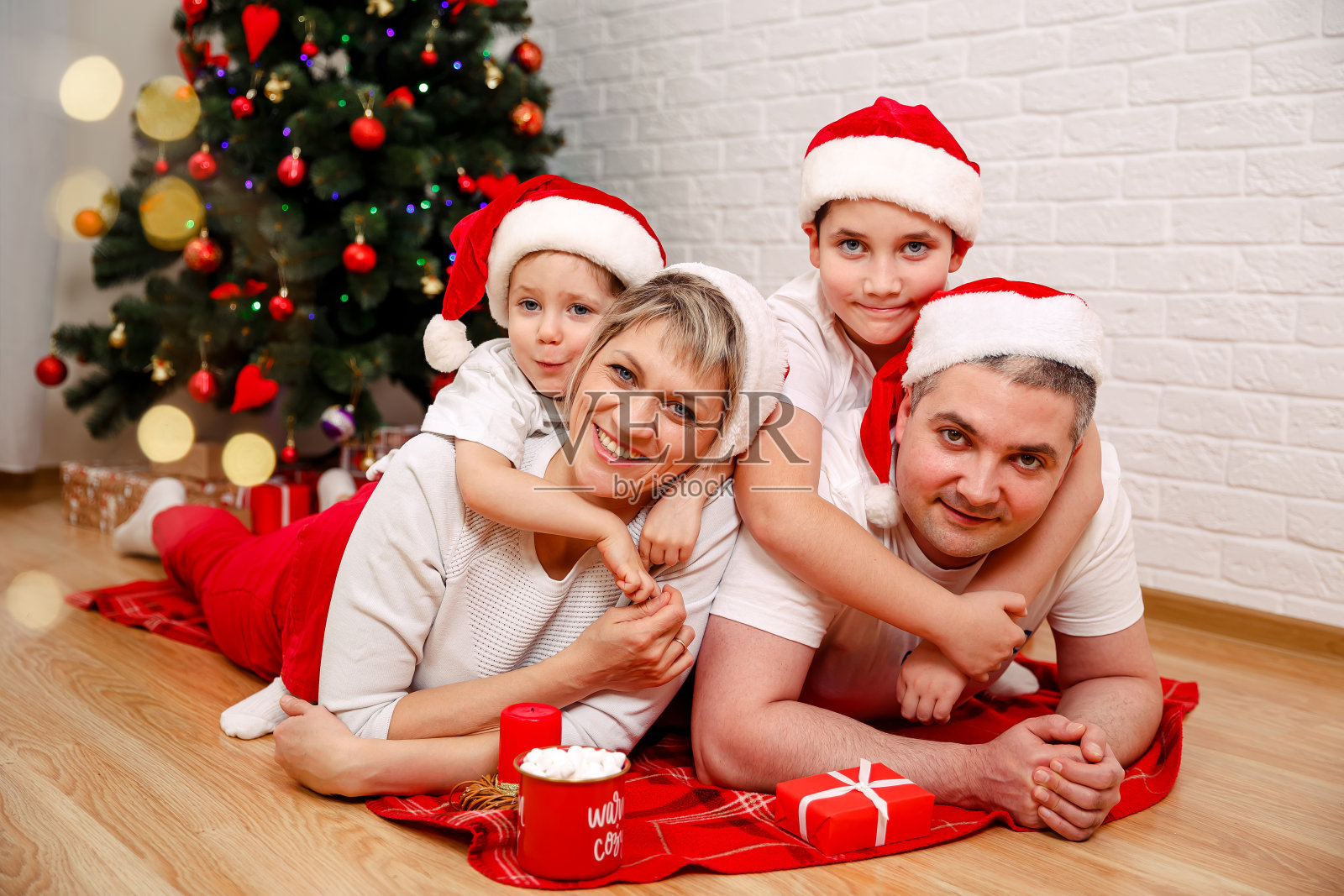 可爱的一家人躺在圣诞树旁的地板上。圣诞节照片摄影图片