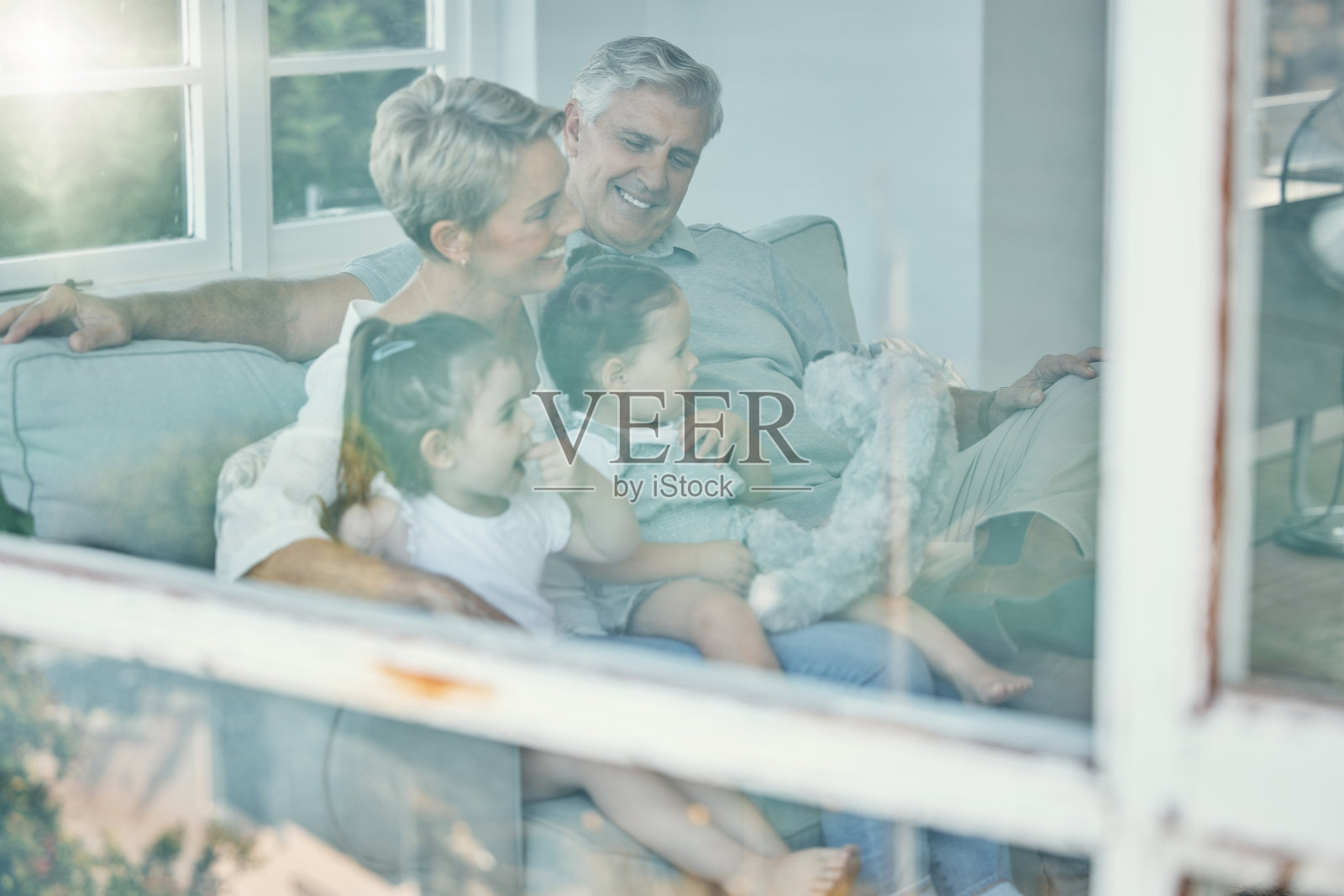 窗户，沙发和祖父母和孩子看电视，放松在家里客厅和流媒体订阅电视电影。幸福的亲情，美好的时光，老人与孙辈的情谊照片摄影图片