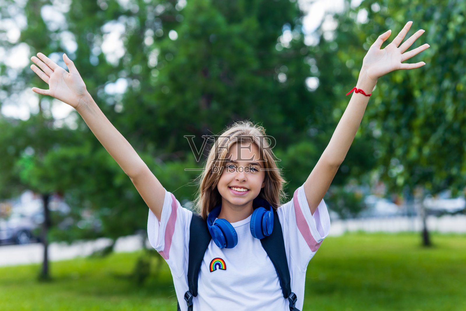 十几岁的女孩带着背包和耳机在公园回到学校的概念照片摄影图片