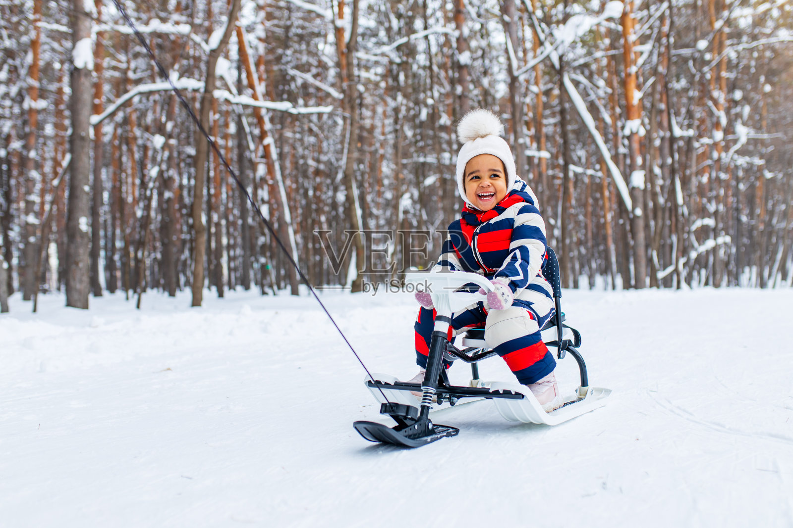小女孩在下雪的冬天在公园玩雪橇下山照片摄影图片