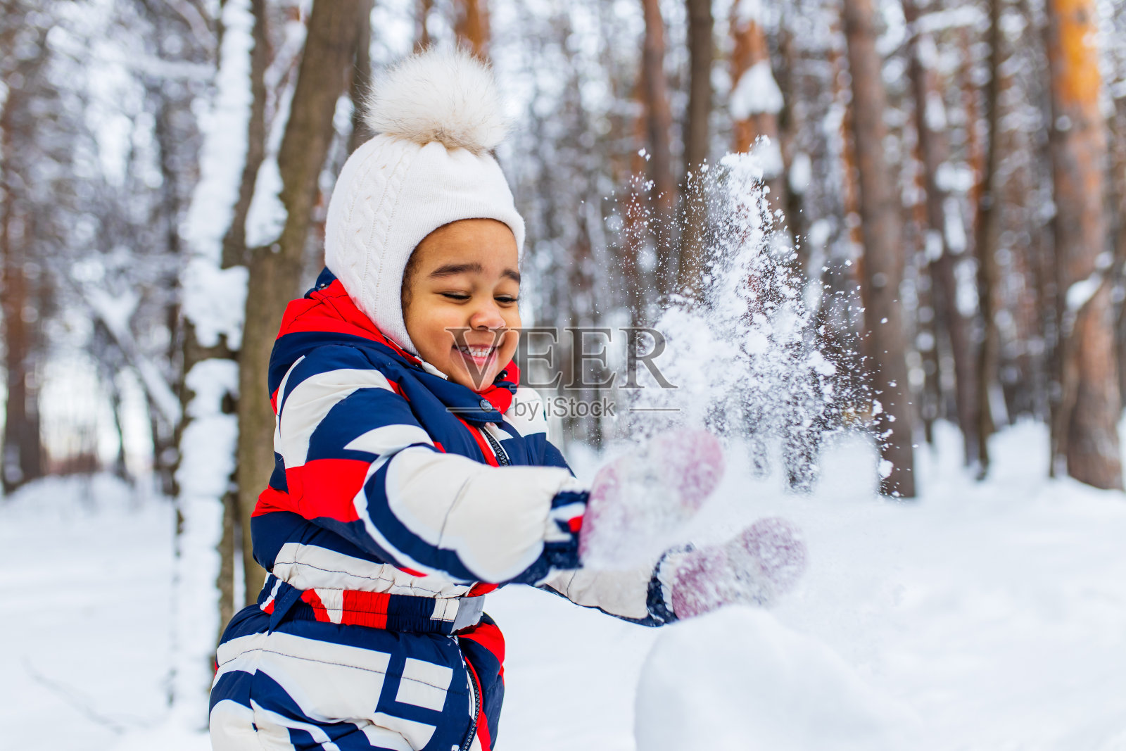 冬天的肖像快乐的小女孩戴着针织帽和一件连体衣在户外的冬天照片摄影图片