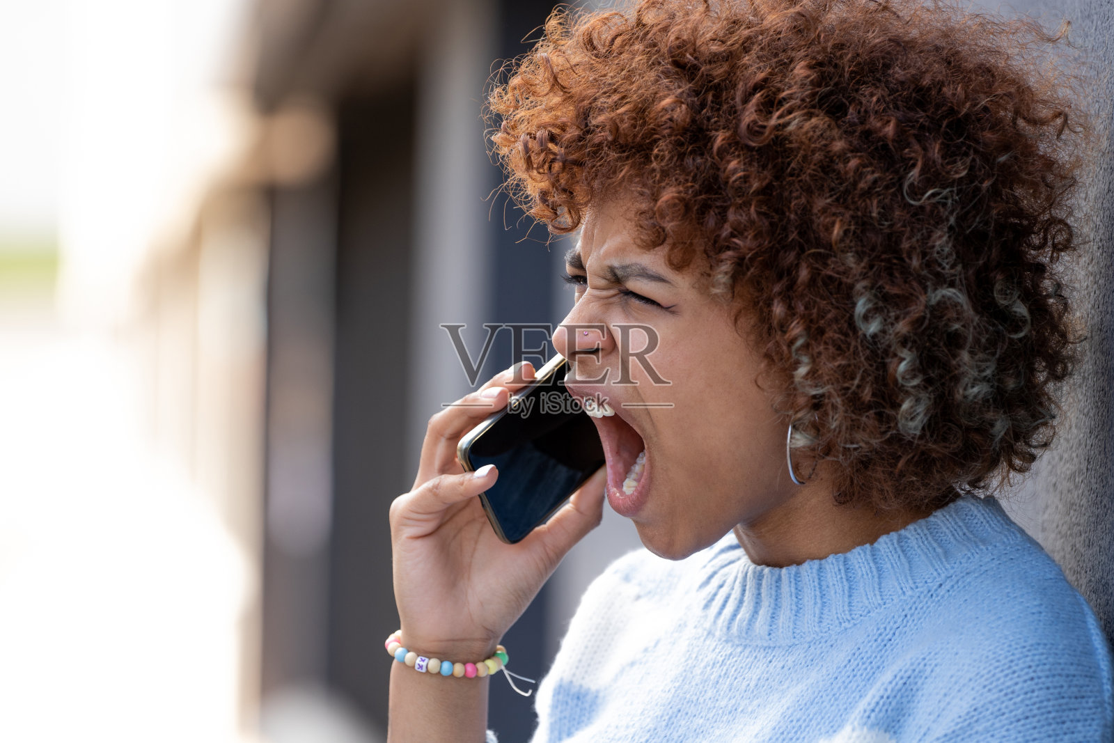 女孩在手机上尖叫，说着愤怒或生气照片摄影图片