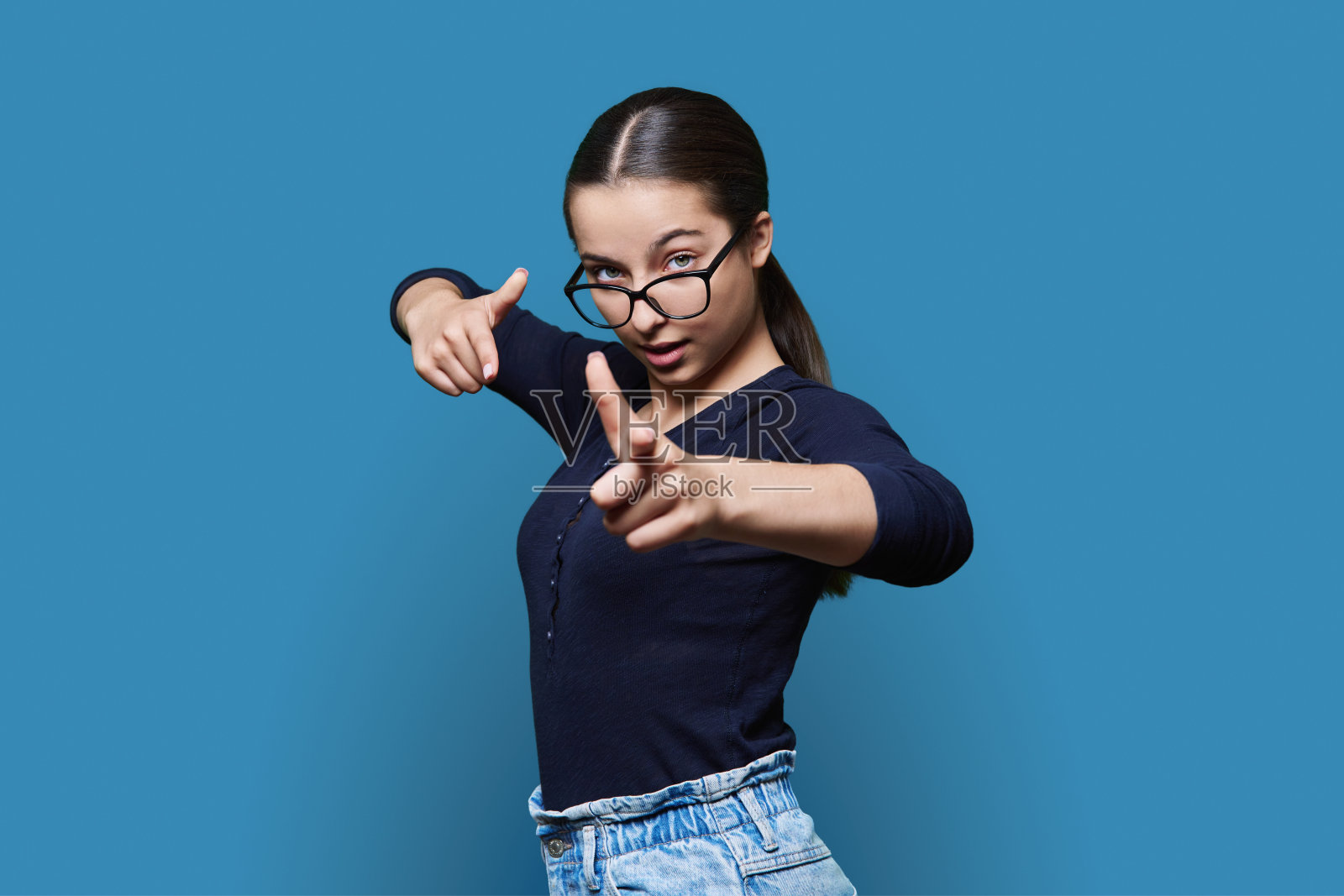 十几岁的女学生看着摄像机指着你照片摄影图片