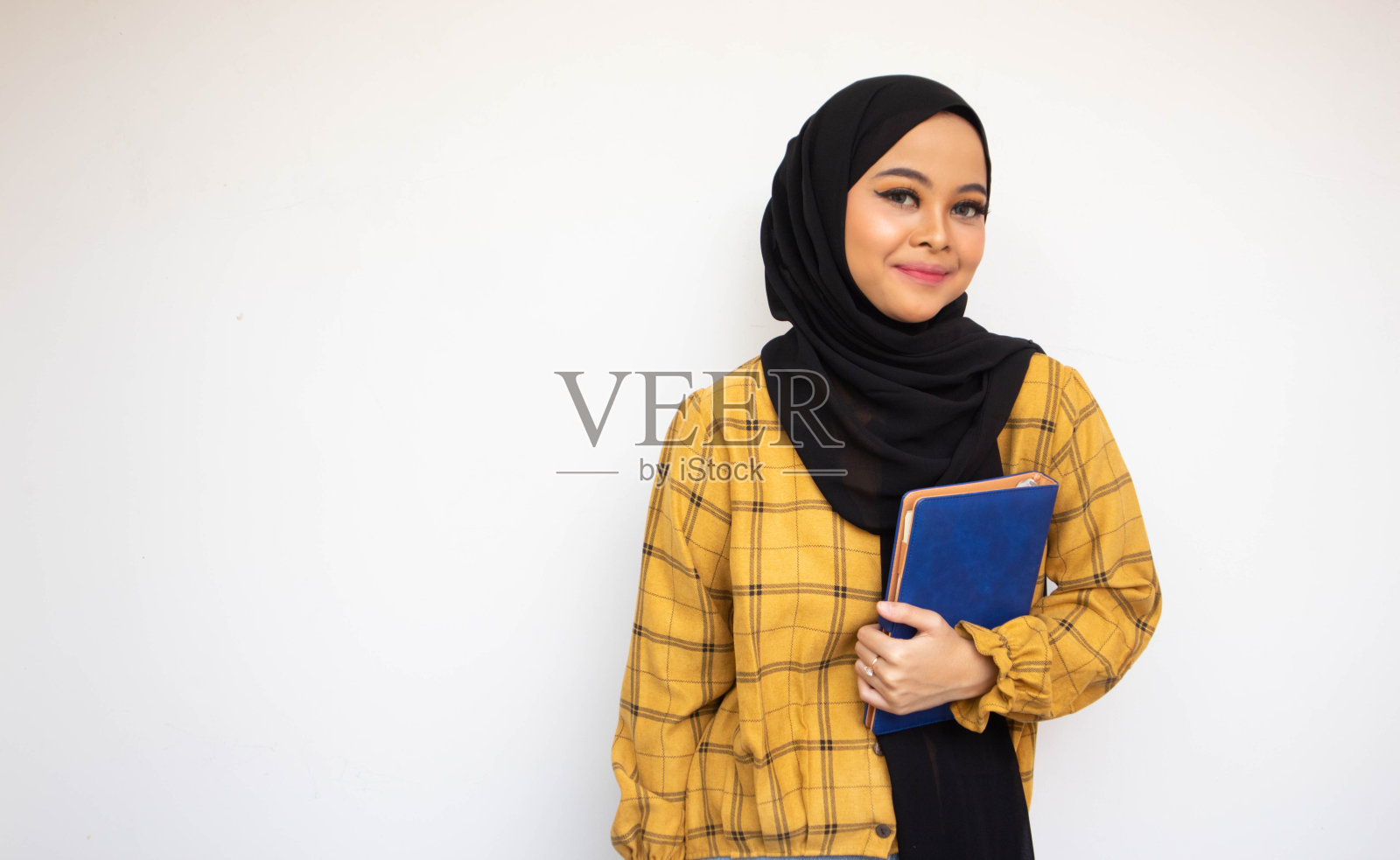 美丽的面纱学生携带书籍微笑看着相机在孤立的背景照片摄影图片