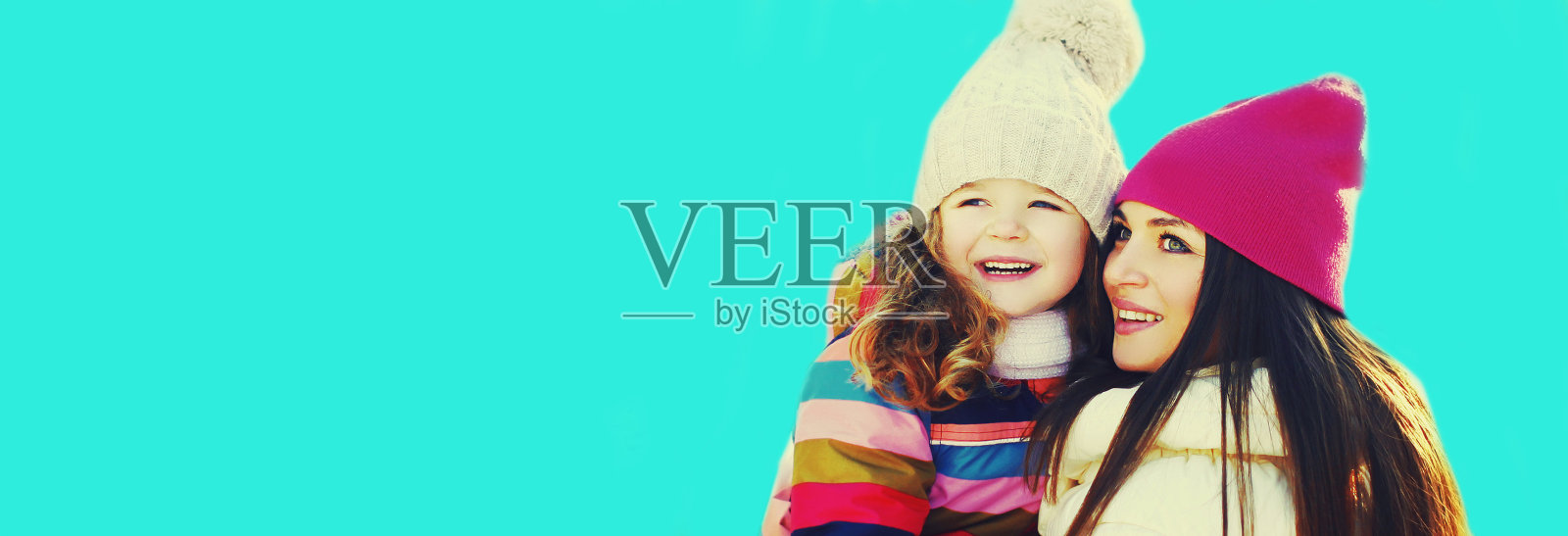 冬天的肖像，快乐的微笑的母亲和小女孩的孩子看着蓝色的背景照片摄影图片