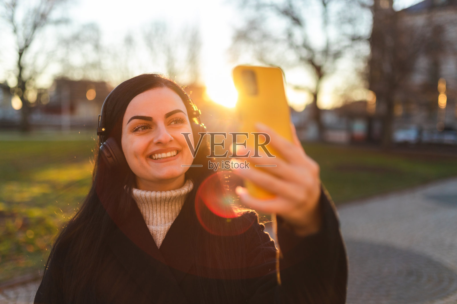 美丽的黑发女子戴着耳机在日落时分自拍照片摄影图片
