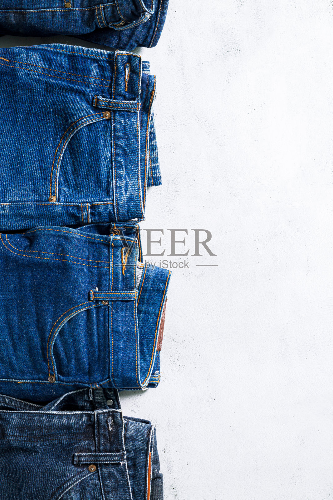 衣服和牛仔裤，堆叠彩色完美折叠的服装项目。白色背景上堆砌不同粉彩的衬衫、孤立的毛衣等服装。缩小，复制空间照片摄影图片