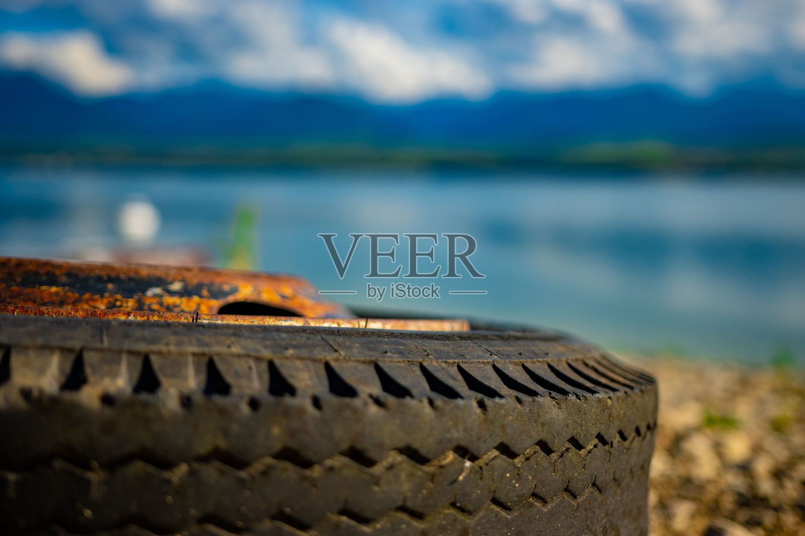 特写镜头的一部分看到的旧和生锈的车轮在海岸上的蓝色大海照片摄影图片